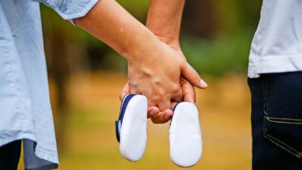 888 and pregnancy - man and woman holding baby shoes